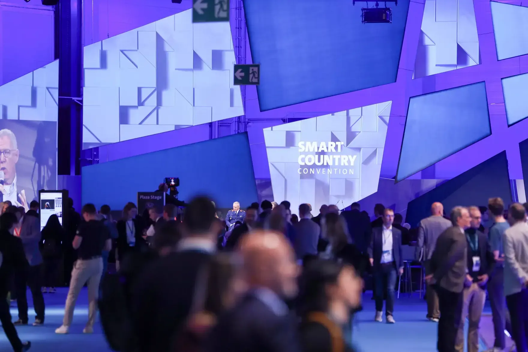Visitors in the exhibition hall of the Smart Country Convention 2026 in Berlin, with the event logo in the background